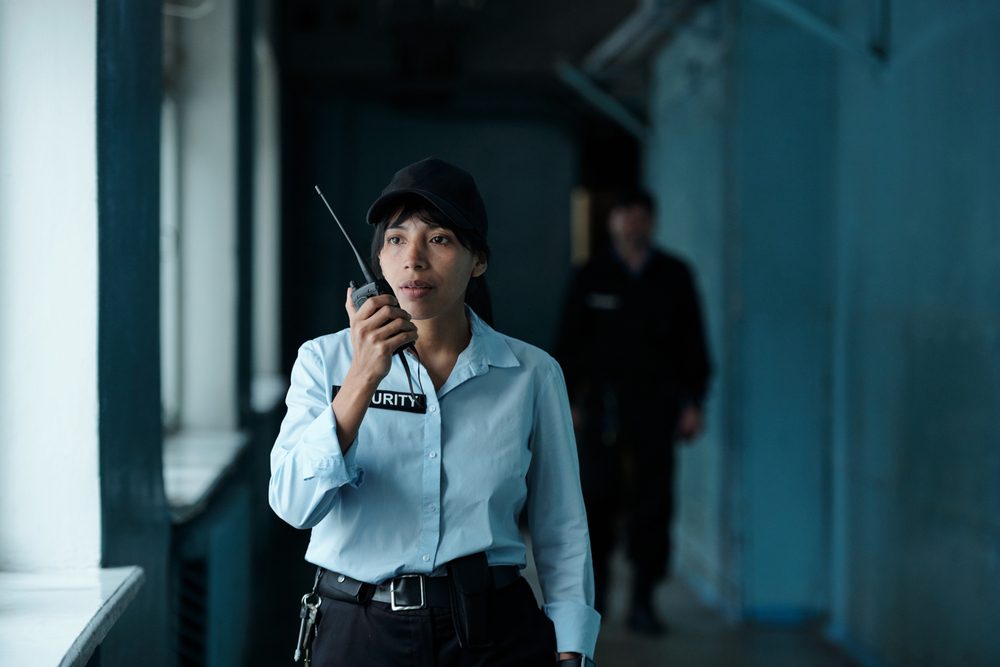 Young,Female,Security,Guard,In,Uniform,And,Cap,Speaking,On