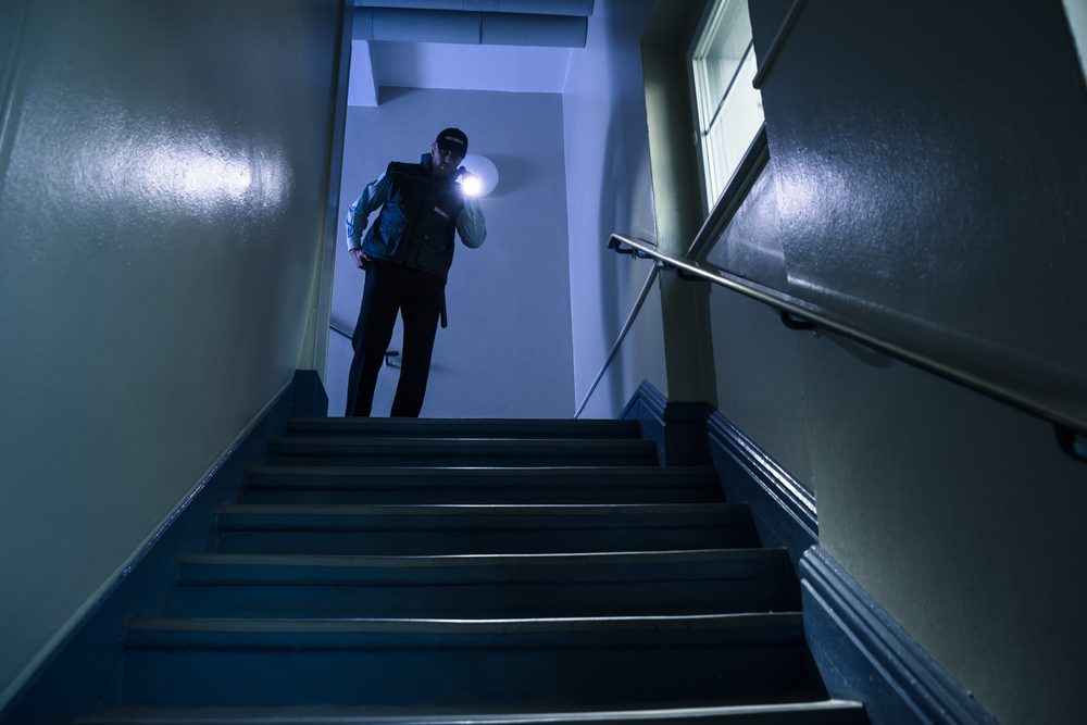 Male,Security,Guard,Searching,On,Stairway,With,Flashlight
