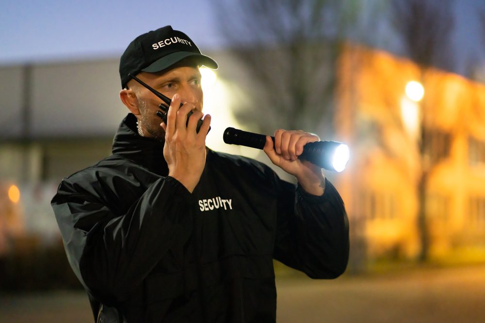 Security,Guard,Walking,Outdoors,With,Flashlight,At,Night
