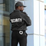 Male,security,guard,standing,near,big,modern,building