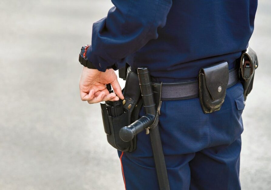 Hand,Of,Police,Officer,Holding,Radio,Set,,Baton,Tonfa,Close
